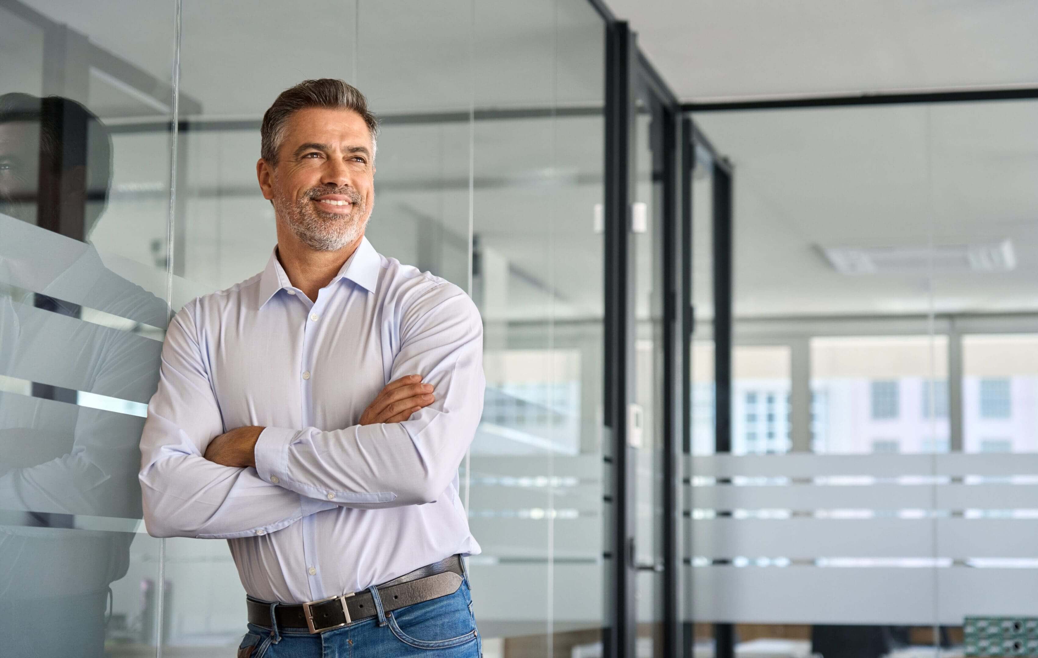 Smiling professional leaning against glass partition